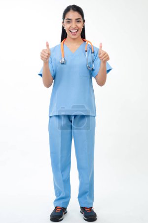 Foto de Young female doctor standing on white background and showing thumbs up - Imagen libre de derechos