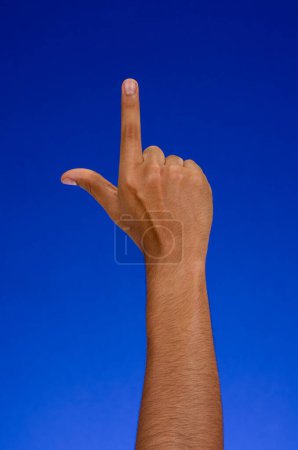 Foto de Raised hand pointing up, on a blue background - Imagen libre de derechos