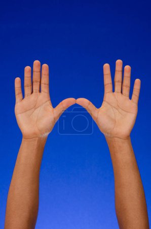 Téléchargez les photos : Empty hands showing palms, thanking, raised to the sky, on blue background - en image libre de droit