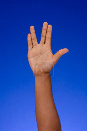 Foto de Dedos y palmas haciendo carteles sobre un fondo azul - Imagen libre de derechos