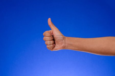 Téléchargez les photos : Thumb up in approval sign, on blue background - en image libre de droit