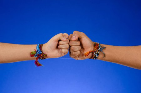 Foto de Young people in bracelets bumping their fists on a blue background - Imagen libre de derechos