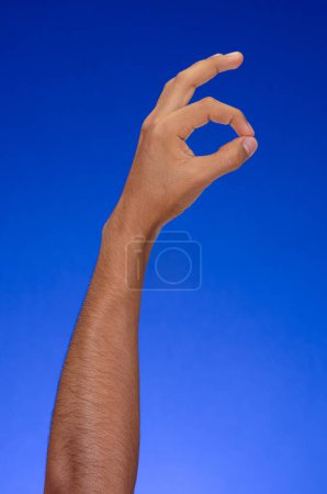 Téléchargez les photos : Hand on a blue background, making Ok gesture - en image libre de droit