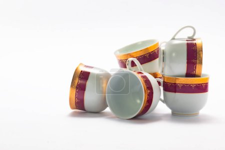 Foto de Set de elegantes tazas de porcelana dorada y roja sobre fondo blanco - Imagen libre de derechos
