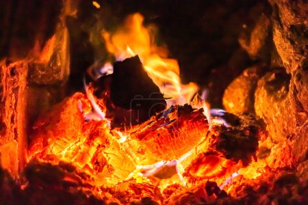 Photo for Beautiful old fireplace with light flame fire for heating building room, old fireplace consisting of thick oak wooden logs in hot flame fire, bright flame fire in old iron fireplace from slice tree - Royalty Free Image