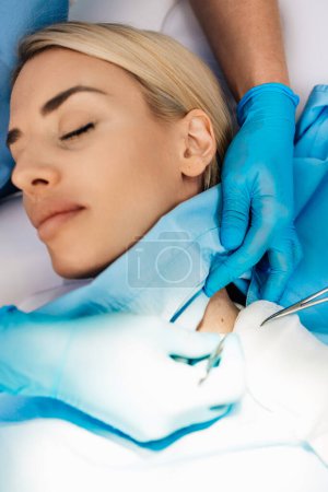 Photo for Beautiful young woman receiving mole or birthmark removal treatment at beauty clinic. Medical surgery for body and face corrections concept. View from above. - Royalty Free Image