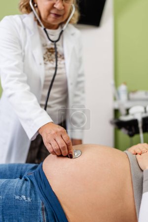 Foto de Doctora haciendo ecografía para una hermosa mujer embarazada. Vista lateral. Embarazo moderno y concepto sanitario. - Imagen libre de derechos