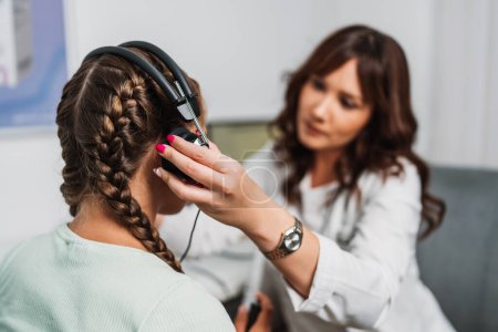 Audiologe, der Impedanzaudiometrie oder die Diagnose einer Hörschädigung durchführt. Ein hübsches Teenager-Mädchen, das in einer Hörklinik einen Hörtest macht. Gesundheits- und Medizinkonzept.