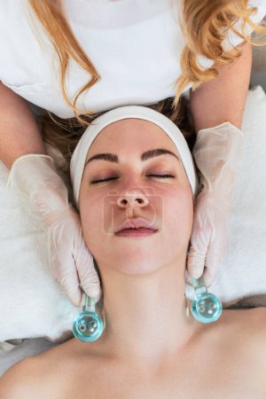 Photo for Beautiful young woman enjoying in cryotherapy with cryo sticks or ice globes. Modern and popular beauty procedure for reducing redness, inflammation and skin puffiness. Skincare treatment concept. - Royalty Free Image