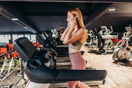 Photo for Beautiful skinny redhead woman exercising in a spacious and modern equipped fitness gym. People and recreation concept. - Royalty Free Image