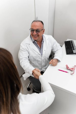 Doctor gynecologist having consultation with patient. The doctor uses the model to explain to the patient the functioning of the female reproductive system, possible problems and their prevention.