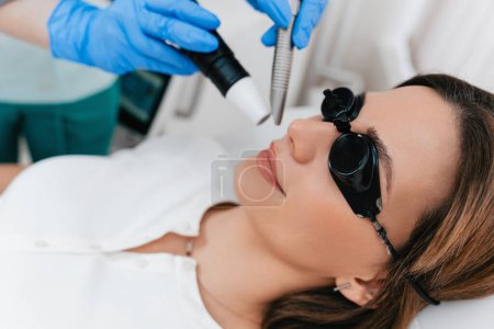 Photo for Beauty laser expert doing a cosmetic skin resurfacing treatment on a beautiful female patient. Modern and popular anti age procedure for removing old and stimulating new tissue creation. - Royalty Free Image