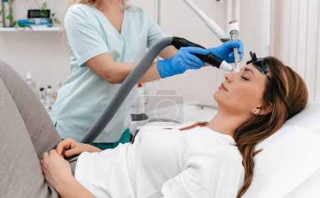 Photo for Beauty laser expert doing a cosmetic skin resurfacing treatment on a beautiful female patient. Modern and popular anti age procedure for removing old and stimulating new tissue creation. - Royalty Free Image
