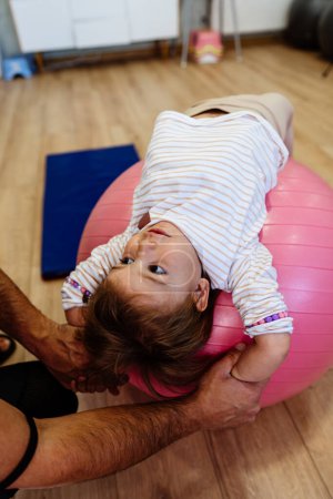 Photo for Adorable girl enjoys physical therapy sessions with a qualified therapist in a specialized children's gym or play area. - Royalty Free Image