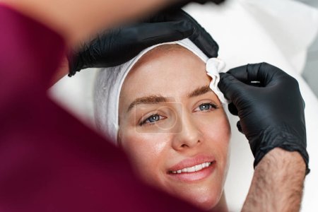 Photo for Attractive woman is getting a rejuvenating facial injections at beauty clinic. The expert beautician is filling female wrinkles with botulinum toxin injections or hyaluronic acid fillers. - Royalty Free Image