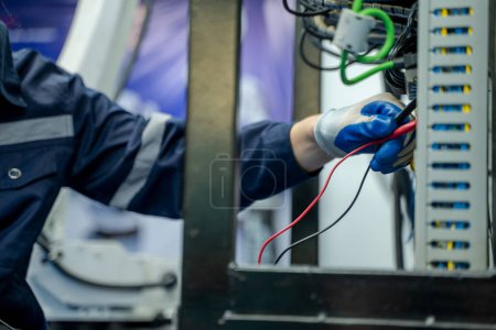 Téléchargez les photos : Ingénieurs électriciens travaillant pour tester la tension et le courant des fils dans l'armoire de commande électrique dans l'usine. - en image libre de droit