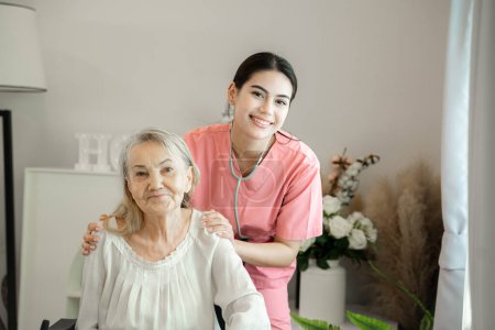 Smiling female caregiver assisting senior grandma helping old patient in rehabilitation recovery at medical checkup visit.