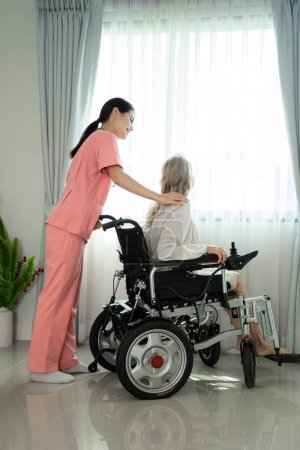 Foto de Amistosa enfermera apoyando a una anciana, disfrutando de un momento tranquilo relajándose juntos. - Imagen libre de derechos