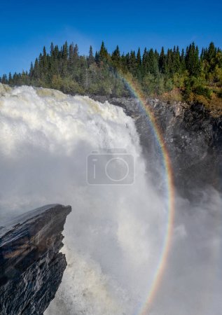 Photo for Famous waterfall Tannforsen in northern Sweden, with a rainbow in the mist and rapid flowing cascades of water. - Royalty Free Image