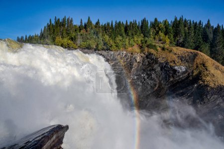Foto de Famosa cascada Tannforsen en el norte de Suecia, con un arco iris en la niebla y cascadas de agua que fluyen rápidamente. - Imagen libre de derechos
