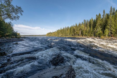 Téléchargez les photos : Célèbre cascade Tannforsen dans le nord de la Suède, avec un arc-en-ciel dans la brume et des cascades d'eau rapides. - en image libre de droit