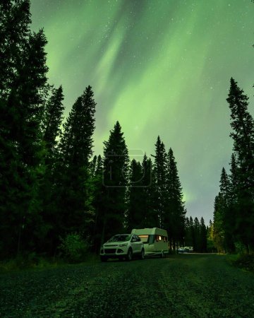 Foto de Aurora brillando sobre Camping Caravan en el paisaje forestal sueco Tannforsen Waterfall Northern Lights color cielo norte de Suecia, Escandinavia. - Imagen libre de derechos