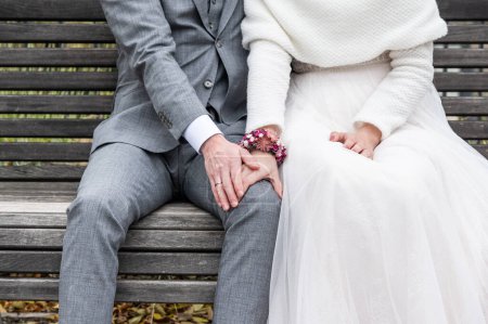 Foto de Novia sosteniendo la mano del novio con anillos de boda sentados en el banco. - Imagen libre de derechos