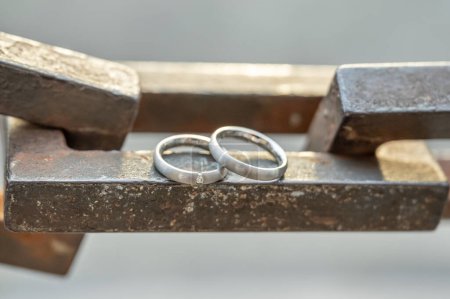 Foto de Dos manos con anillos de boda descansan sobre una fuerte cadena de anclaje. - Imagen libre de derechos