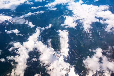Téléchargez les photos : Belle vue fenêtre sur les nuages pelucheux et les montagnes des Alpes depuis le siège passager de l'avion. Voyages et transport aérien. - en image libre de droit