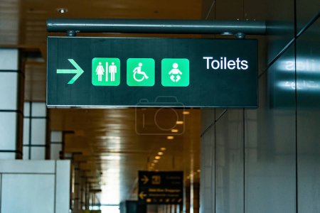 Téléchargez les photos : Panneau de toilette sur le plafond de l'entrée de la salle de bain dans l'aéroport signe de toilette concept. Icônes prêtes. Toilettes pour hommes et femmes. - en image libre de droit