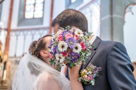 Téléchargez les photos : Bouquet de mariage au premier plan d'un couple de baisers flous. Fleurs et amoureux. - en image libre de droit