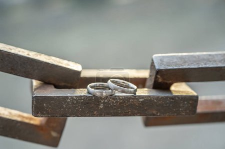Foto de Dos manos con anillos de boda descansan sobre una fuerte cadena de anclaje. - Imagen libre de derechos