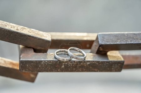 Photo for Two hands with wedding rings rest on a strong anchor chain. - Royalty Free Image