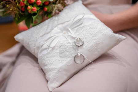 Foto de Dos anillos de boda en una almohada de cojín ceremonial bellamente decorado. - Imagen libre de derechos
