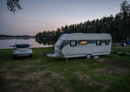 Téléchargez les photos : Camping de nuit caravane au bord du lac Ragnerudssjoen en Dalsland Suède belle forêt naturelle pinetree. - en image libre de droit