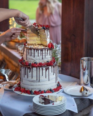Téléchargez les photos : Mariage marié et marié Couper le délicieux gâteau de mariage fruité ensemble fruits colorés. - en image libre de droit
