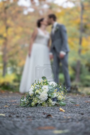Téléchargez les photos : Bouquet de mariage au premier plan d'un couple de baisers flous. Fleurs et amoureux. - en image libre de droit