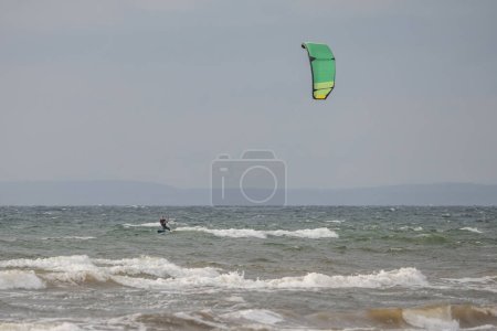 Foto de Melbystrand Suecia Un kitesurfista practica sus habilidades de surf cerca de la playa con dunas de arena. - Imagen libre de derechos
