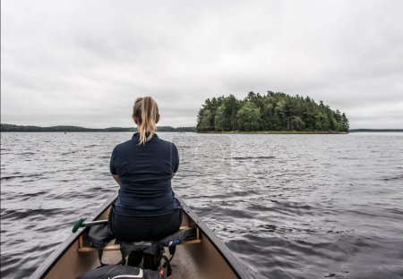 Téléchargez les photos : Blonde Promenade en canot explorant la nature sur la rivière et les îles dans la brume matinale au parc national Kejimkujik Nature sauvage désignée Nouvelle-Écosse Canada - en image libre de droit