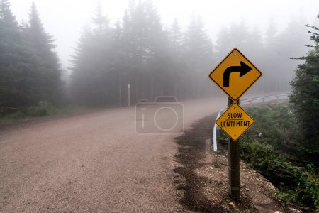 Téléchargez les photos : Panneau Lentement lent Panneau d'avertissement des routes jaunes en vue de mise au point sélective avec route en arrière-plan par temps brumeux Île du Cap-Breton Nouvelle-Écosse Highlands Canada - en image libre de droit