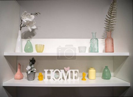 Photo for Shabby chic interior decor in pitcher, lantern and wooden letters on a vintage shelf over pastel wall home decoration. - Royalty Free Image