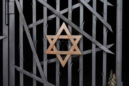 Téléchargez les photos : Une étoile juive de David, en métal doré sur une clôture en métal noir Dachau. - en image libre de droit
