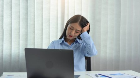 Photo for Asian woman sitting and working has a headache. - Royalty Free Image