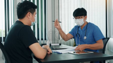 Téléchargez les photos : Les médecins expliquent le traitement de la maladie d'un patient tout en portant un masque pendant l'épidémie. - en image libre de droit