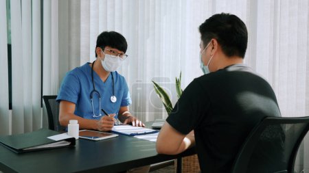 Téléchargez les photos : Les médecins expliquent le traitement de la maladie d'un patient tout en portant un masque pendant l'épidémie. - en image libre de droit