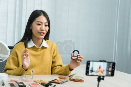 Téléchargez les photos : Asiatiques adolescentes faisant maquillage vlogs et en utilisant une caméra vidéo mobile pour enregistrer vlogs et les publier en ligne à la maison. - en image libre de droit