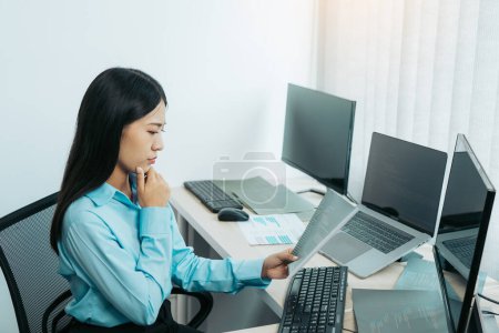Téléchargez les photos : Concentré asiatique femme brainstorming tout en codant les données sur PC de bureau tout en travaillant sur les codes informatiques dans le bureau. - en image libre de droit