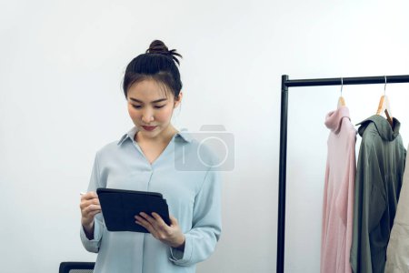 Téléchargez les photos : Jeunes entrepreneurs asiatiques utilisent une tablette tout en vérifiant les bons de commande en ligne. - en image libre de droit