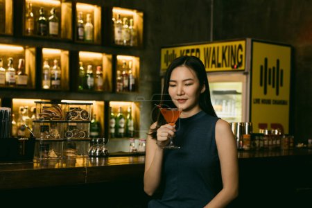 Téléchargez les photos : Asiatique femme boire un cocktail dans un bar la nuit. - en image libre de droit