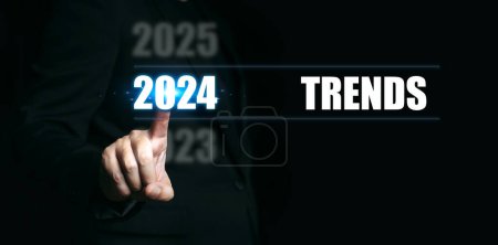 Téléchargez les photos : Nouvel an 2024 avec tendance. Homme d'affaires pointant vers les chiffres de l'année pour fixer la tendance pour l'année à venir. - en image libre de droit